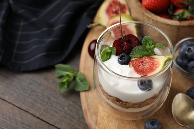 Glass with yogurt, berries and mint on wooden table, closeup. Space for text