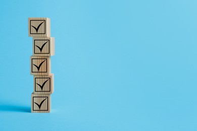 Image of Stacked wooden cubes with check marks on light blue background. Space for text