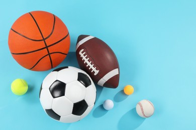 Photo of Many different sports balls on light blue background, flat lay. Space for text