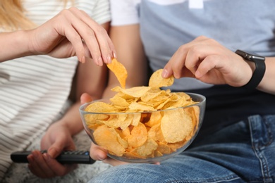 Young couple eating chips while watching TV, closeup view