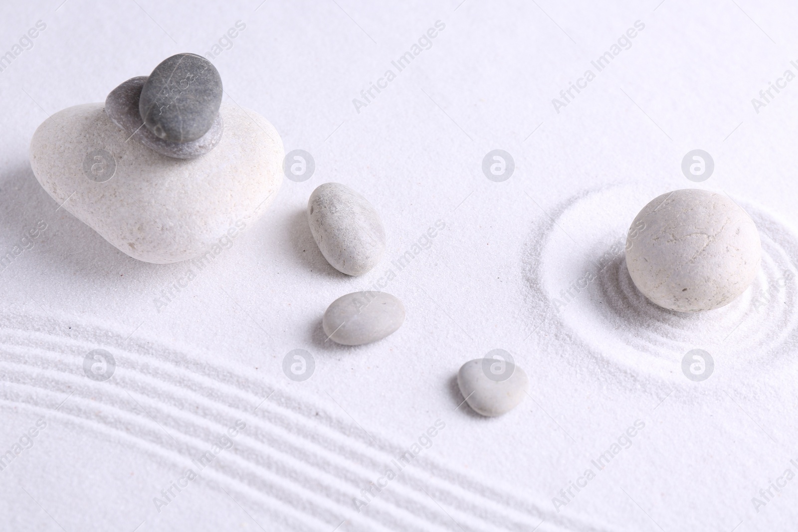 Photo of Zen garden stones on white sand with pattern, flat lay