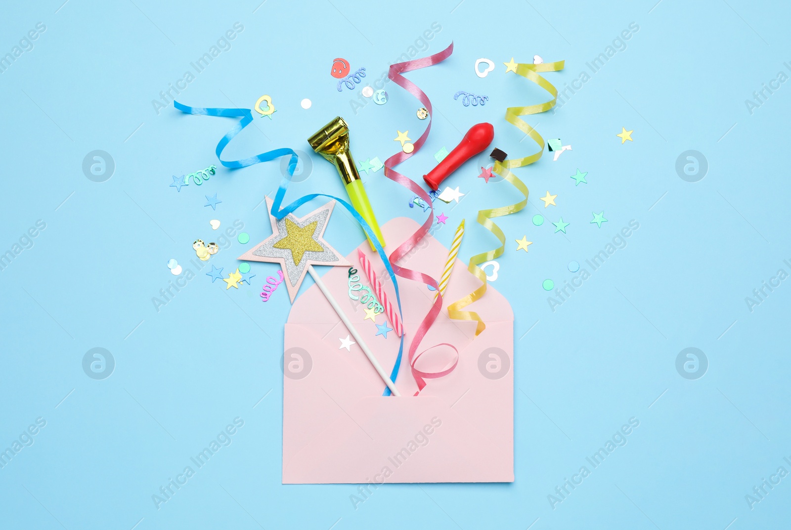 Photo of Envelope with confetti and serpentine streamers on light blue background, top view. Surprise party