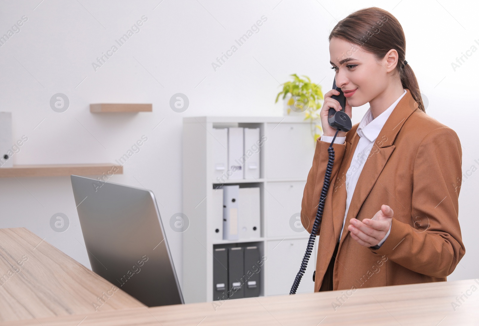 Photo of Female receptionist talking on phone at workplace