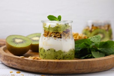 Delicious dessert with kiwi, yogurt and muesli on wooden board, closeup