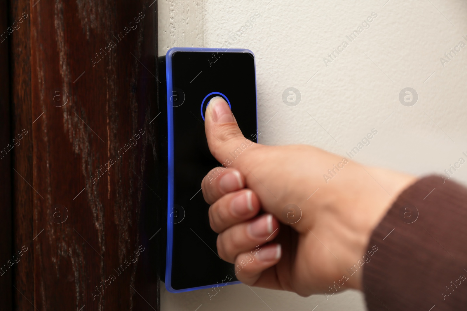 Photo of Woman scanning fingerprint on alarm system indoors, closeup