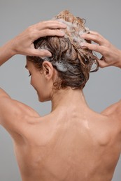 Photo of Woman washing hair on light grey background, back view