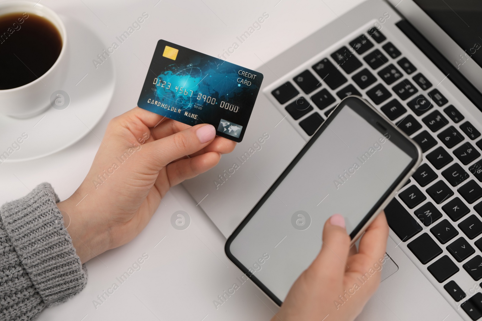 Photo of Woman with credit card using smartphone for online shopping at white table, closeup