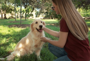 Cute golden retriever dog giving paw to young woman in park