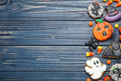 Photo of Tasty cookies and sweets for Halloween party on blue wooden table, flat lay. Space for text
