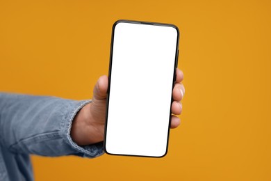 Photo of Man showing smartphone on orange background, closeup. Mockup for design