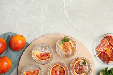 Photo of Delicious refreshing drink with sicilian orange on light grey marble table, flat lay. Space for text