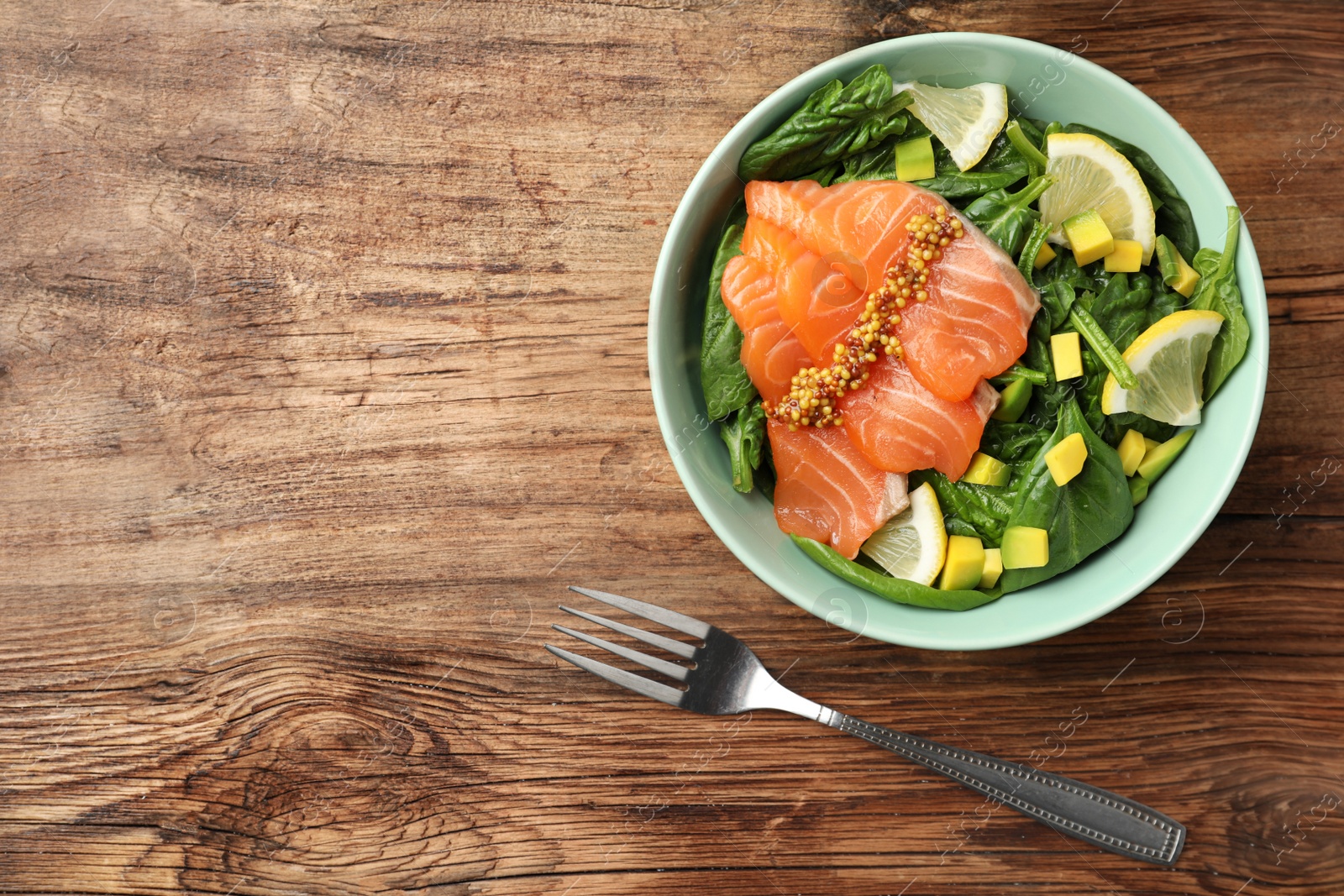 Photo of Delicious fresh salmon with spinach, lemon and avocado served on wooden table, flat lay. Space for text