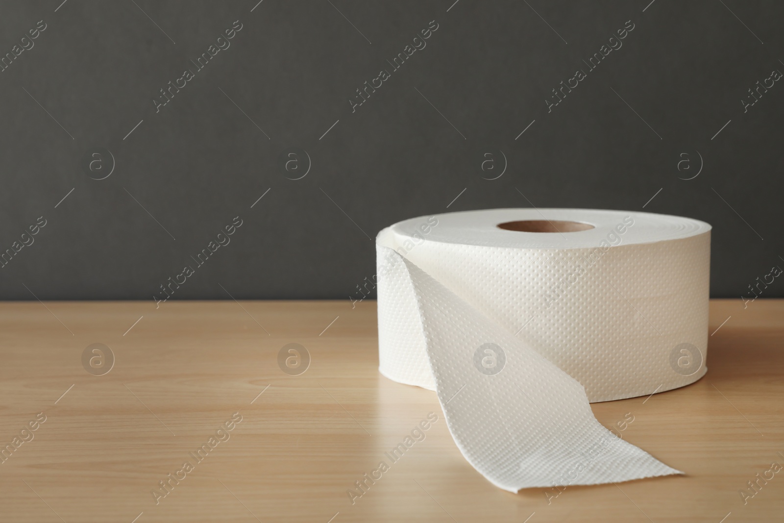 Photo of Soft toilet paper roll on wooden table. Space for text