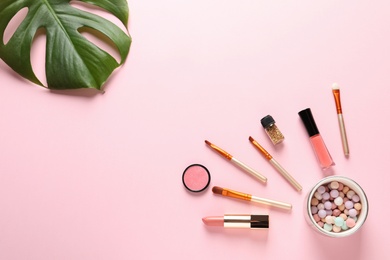 Flat lay composition with products for decorative makeup on pastel pink background