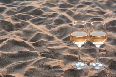 Photo of Glassestasty wine on sand, space for text