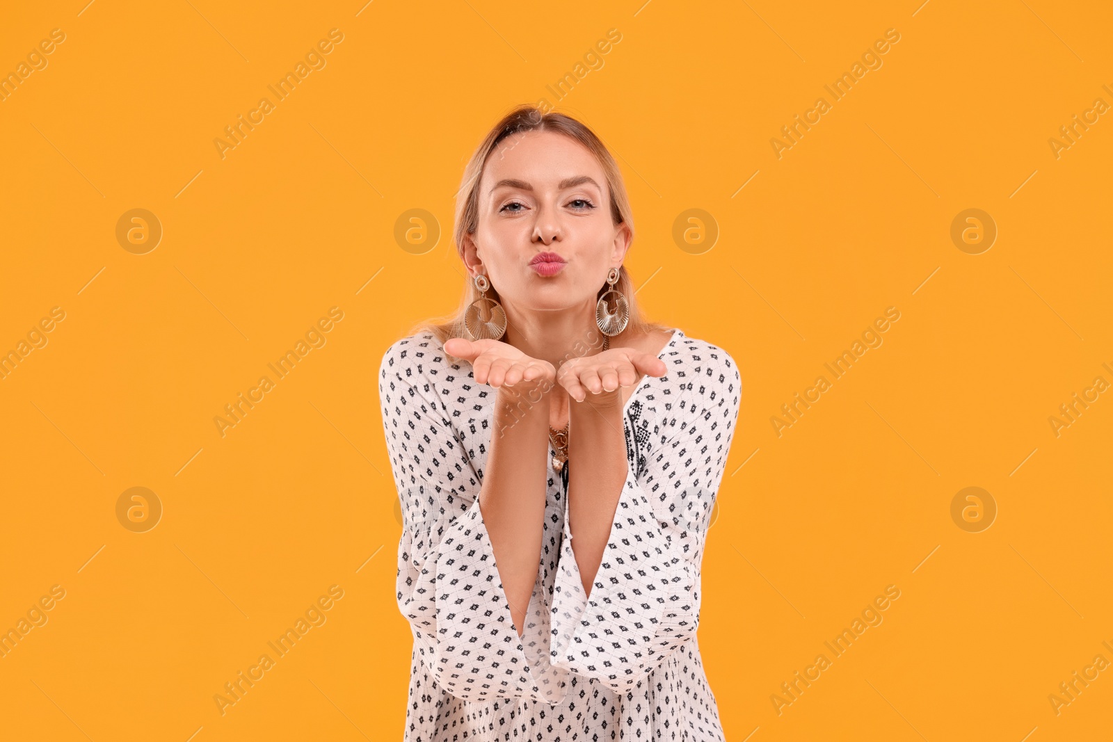 Photo of Portrait of beautiful hippie woman blowing kiss on yellow background