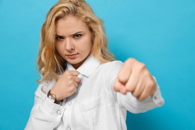 Photo of Young woman ready to fight on light blue background