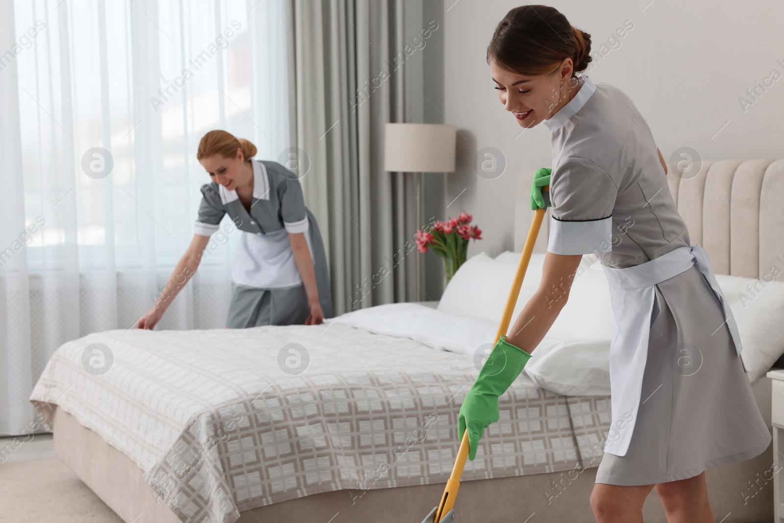Photo of Professional chambermaids cleaning up bedroom in hotel