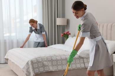 Professional chambermaids cleaning up bedroom in hotel