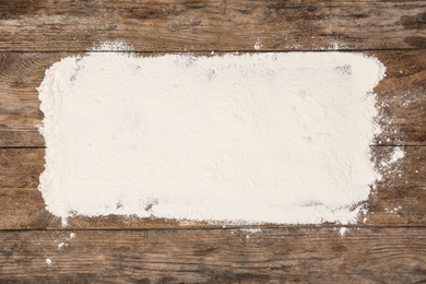 Photo of Pile of flour on wooden table, top view
