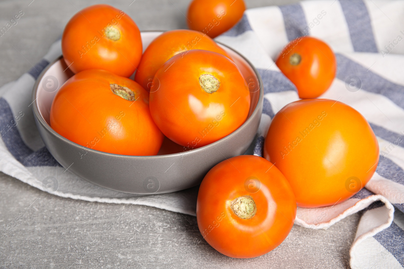 Photo of Many ripe yellow tomatoes on grey table