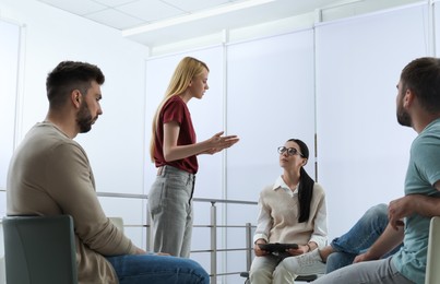 Psychotherapist working with group of drug addicted people at therapy session indoors