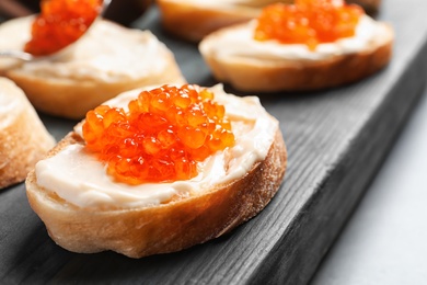 Photo of Delicious sandwich with red caviar on wooden board, closeup