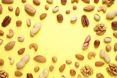 Different delicious nuts on yellow background, flat lay. Space for text