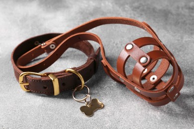 Photo of Brown leather dog muzzle and collar on light gray textured table