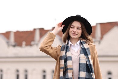 Beautiful woman in warm scarf and hat outdoors, space for text