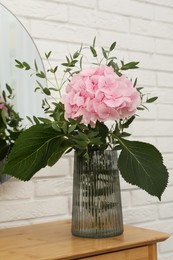 Photo of Beautiful pink hortensia flowers in vase on dressing table indoors