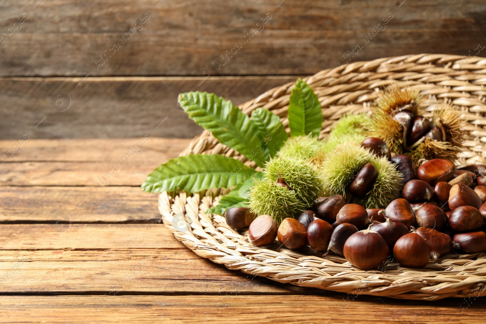 Photo of Fresh sweet edible chestnuts on wooden table. Space for text