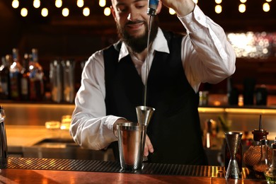 Bartender making fresh alcoholic cocktail at bar counter, selective focus