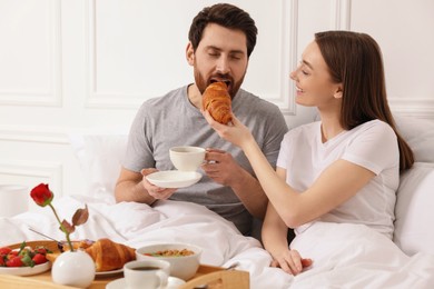 Photo of Tasty breakfast. Wife feeding her husband in bed at home. Space for text