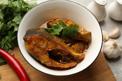 Photo of Tasty fish curry and ingredients on light grey table, closeup. Indian cuisine