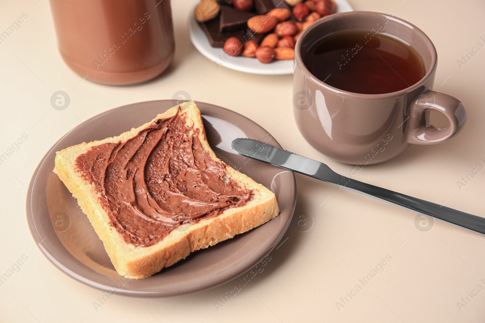 Photo of Tasty toast with chocolate paste and cup of tea served on light table