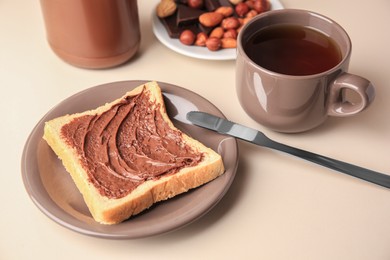 Photo of Tasty toast with chocolate paste and cup of tea served on light table