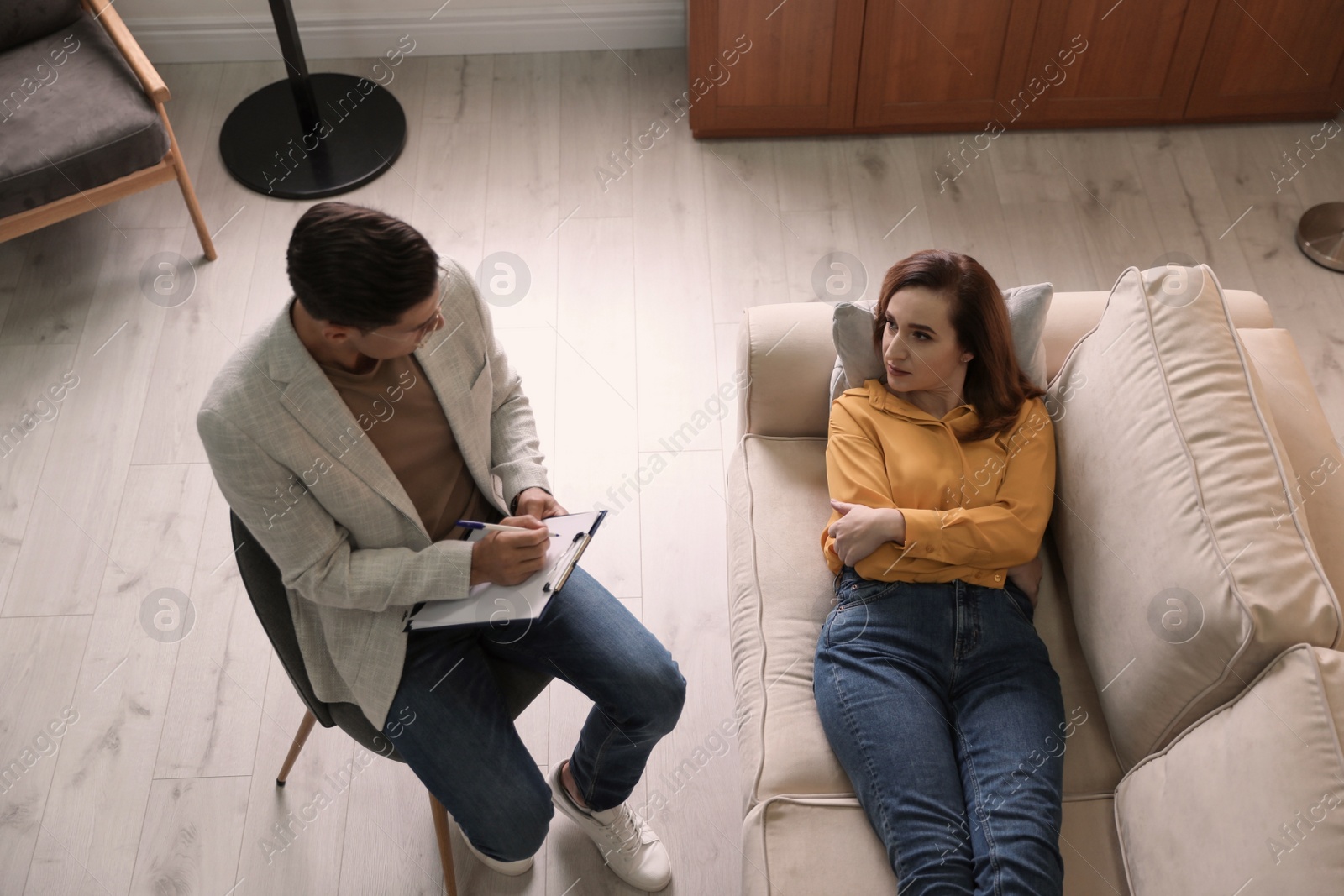 Photo of Professional psychotherapist working with patient in office, above view