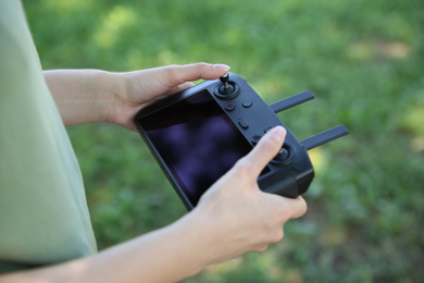 Photo of Woman holding new modern drone controller outdoors, closeup of hands