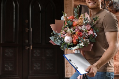 Delivery man with beautiful flower bouquet outdoors, closeup