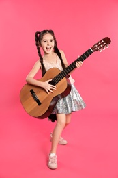 Cute little girl playing guitar on color background