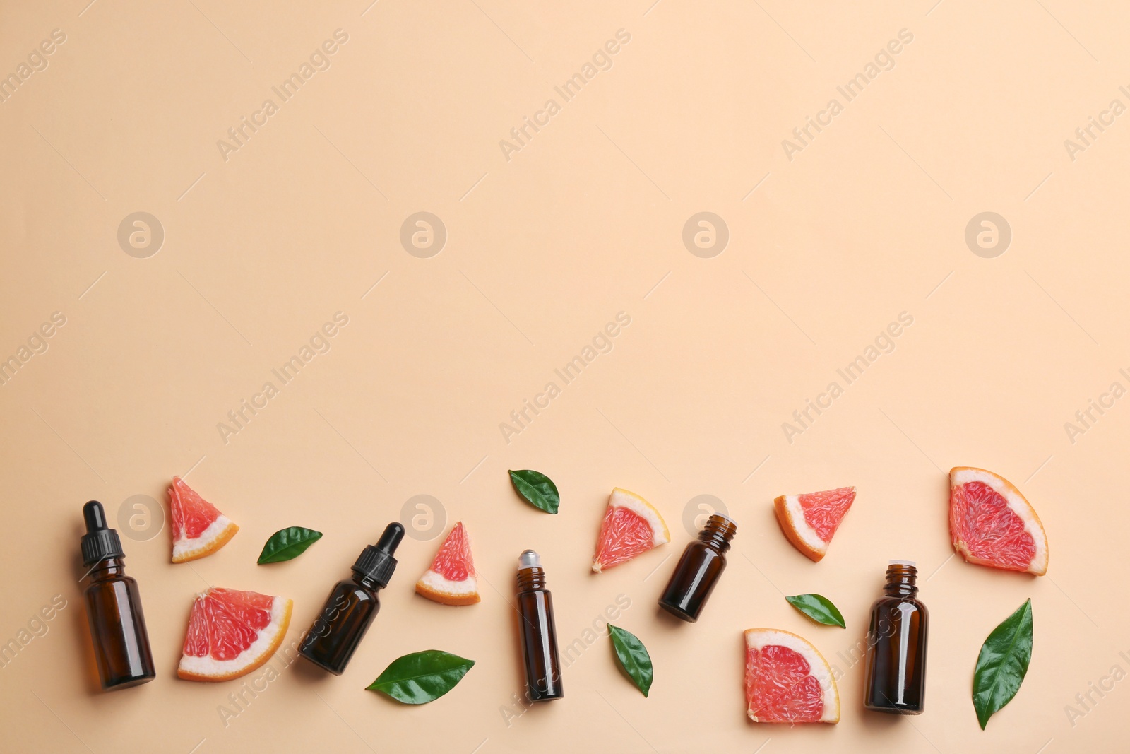 Photo of Flat lay composition with grapefruit slices and bottles of essential oil on color background, space for text