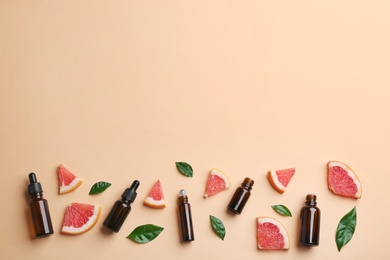 Photo of Flat lay composition with grapefruit slices and bottles of essential oil on color background, space for text