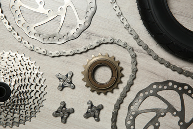 Set of different bicycle parts on wooden background, flat lay