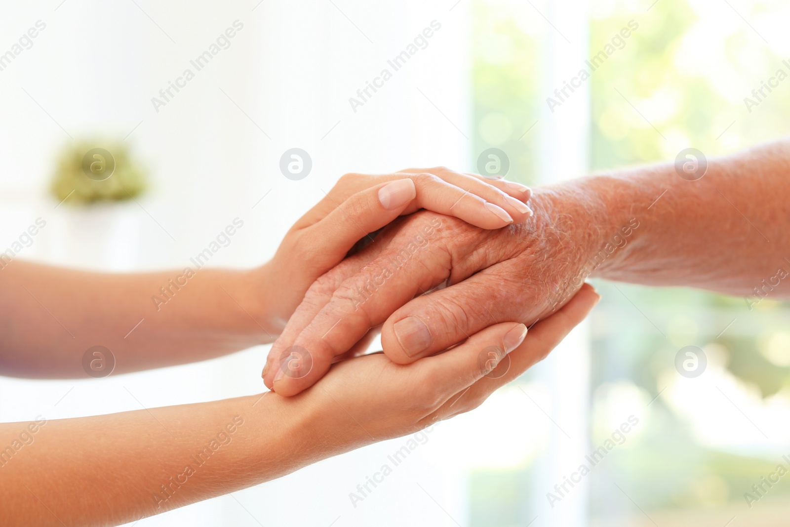 Photo of Helping hands on blurred background, closeup. Elderly care concept