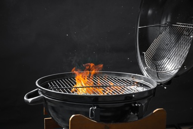 Photo of Modern barbecue grill with burning fire on dark background