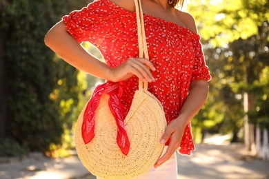 Young woman with stylish straw bag in park, closeup
