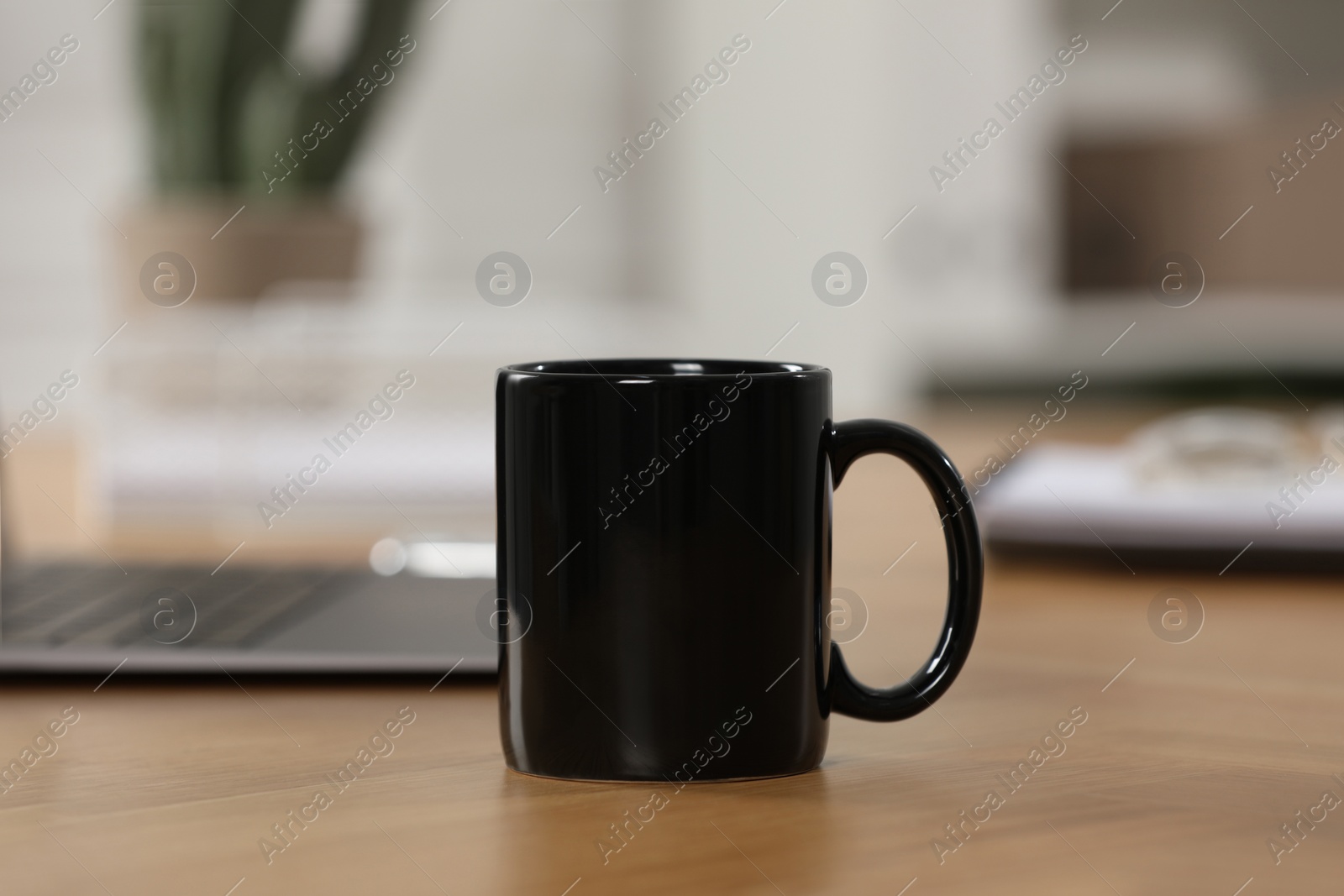 Photo of Black ceramic mug on wooden table at workplace