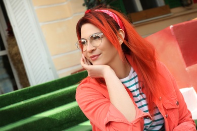 Photo of Young woman with bright dyed hair on stairs outdoors
