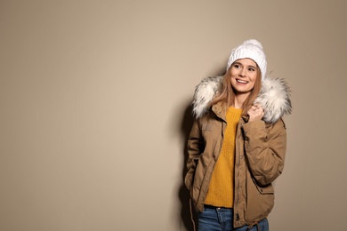 Photo of Young woman wearing warm clothes on color background, space for text. Ready for winter vacation